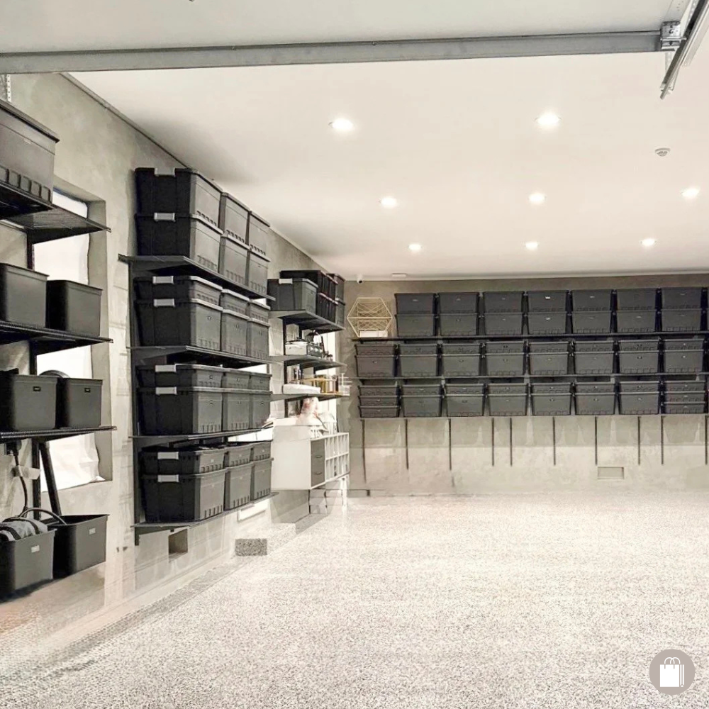Empty garage with black storage bins on shelves and wall-mounted racks.