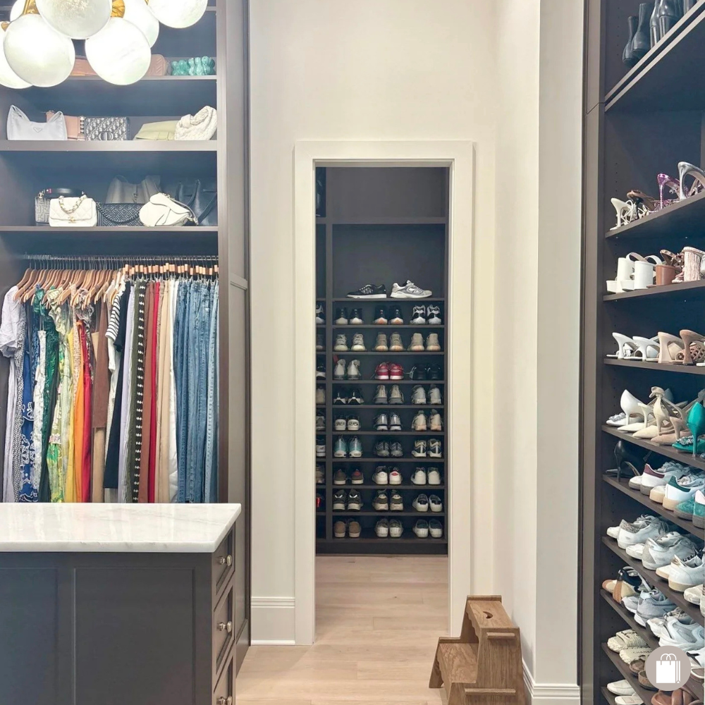 Walk-in closet with shelves of shoes, hanging clothes, handbags, and a small wooden step stool.