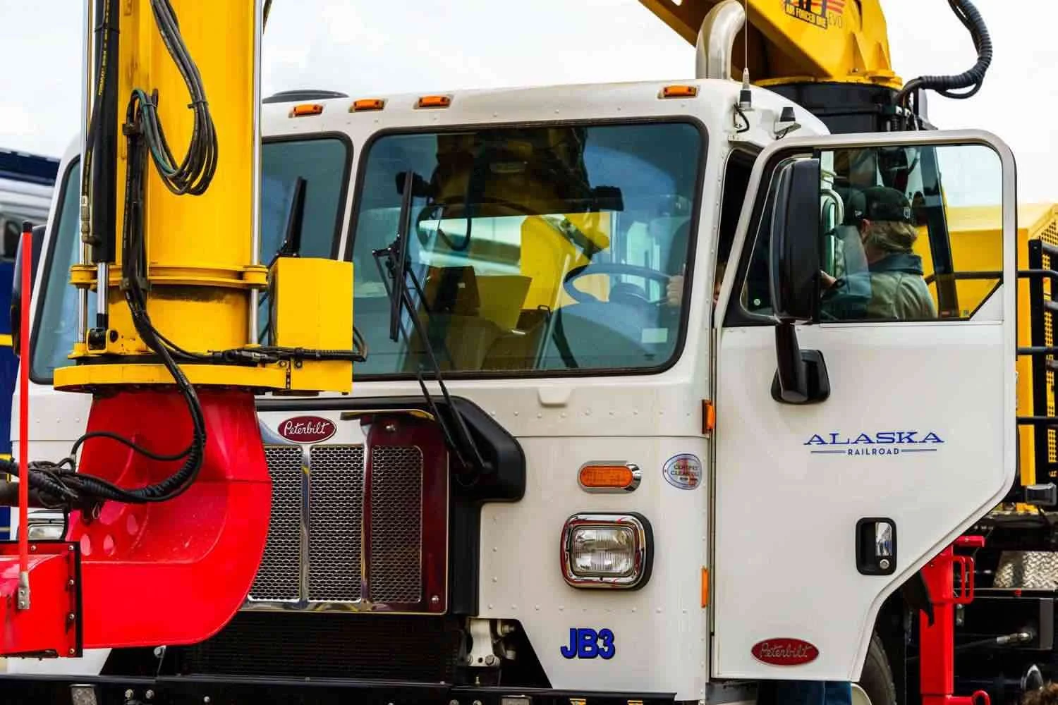 white truck with a yellow and red mechanical arm.jpeg