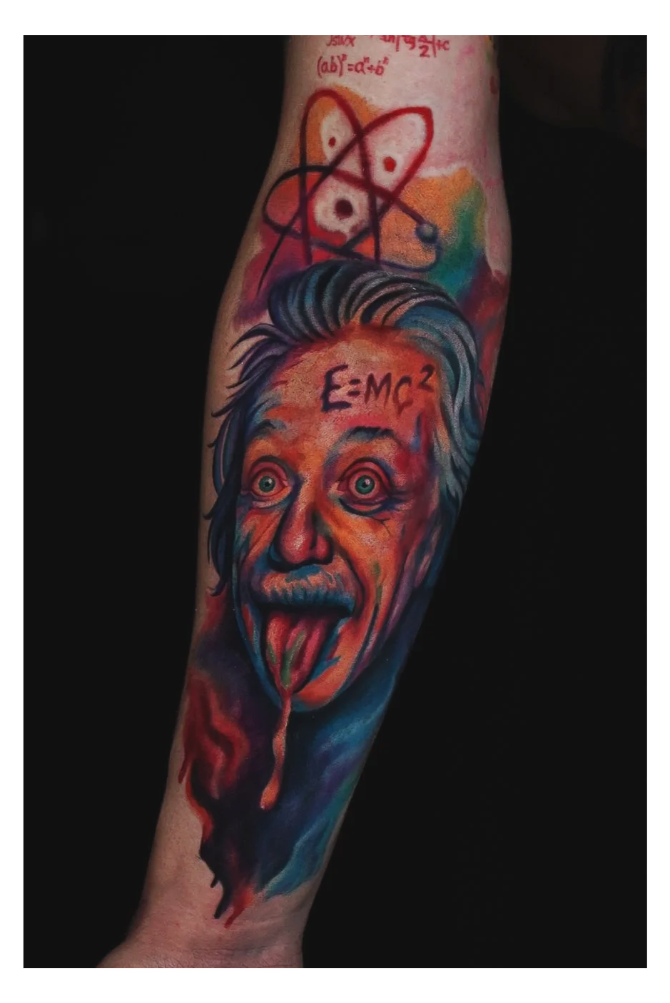 Colorful tattoo of Albert Einstein's face with his tongue sticking out, with the equation E=mc² above his head and a chemical atom symbol above that.