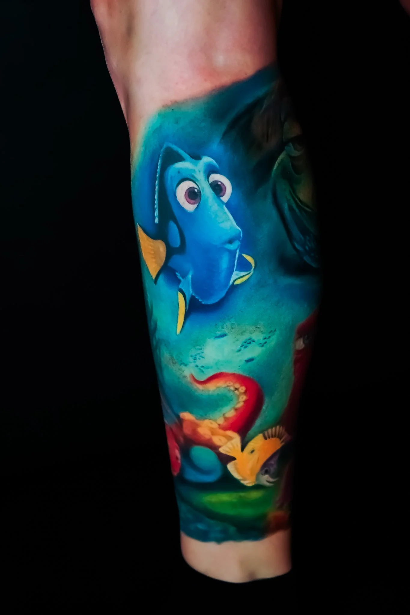 Colorful tattoo sleeve featuring characters from Finding Nemo, including Dory and Nemo, with ocean-themed background and coral.