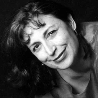 Black and white portrait of a woman with wavy hair smiling at the camera.