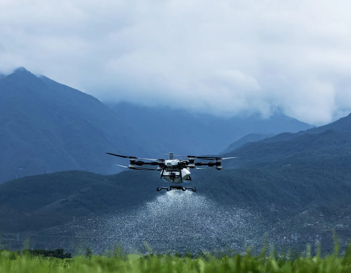 DJI Agras T100 agricultural drone spraying over a field
