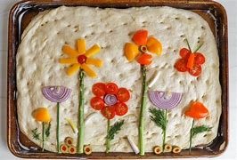 Focaccia Art and Sip class shows focaccia decorated with colorful flowers and butterflies made from icing