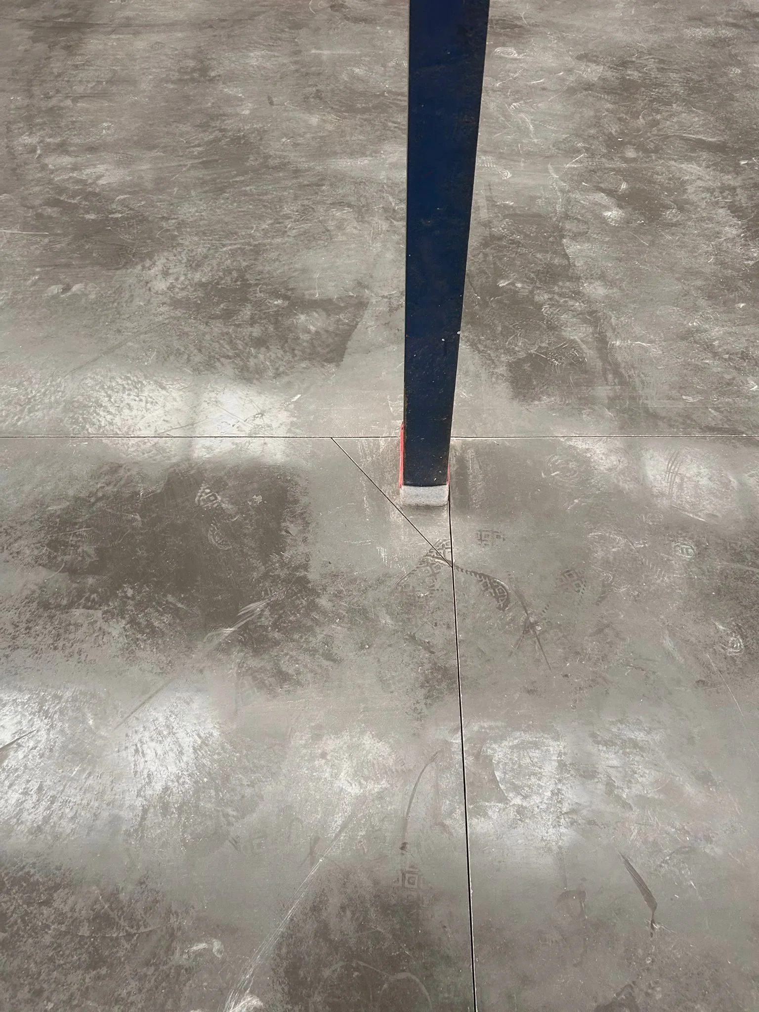 Een atletiekbaan met een blauwe stip of markering in het midden van een betonnen vloer.