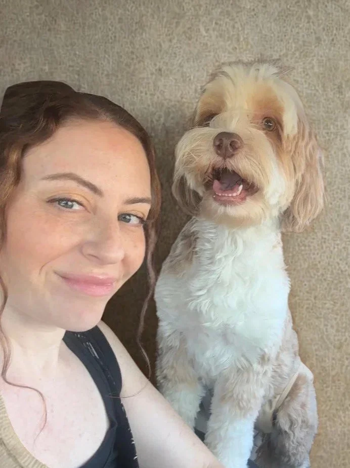 A young woman sitting with an Australian labradoodle 