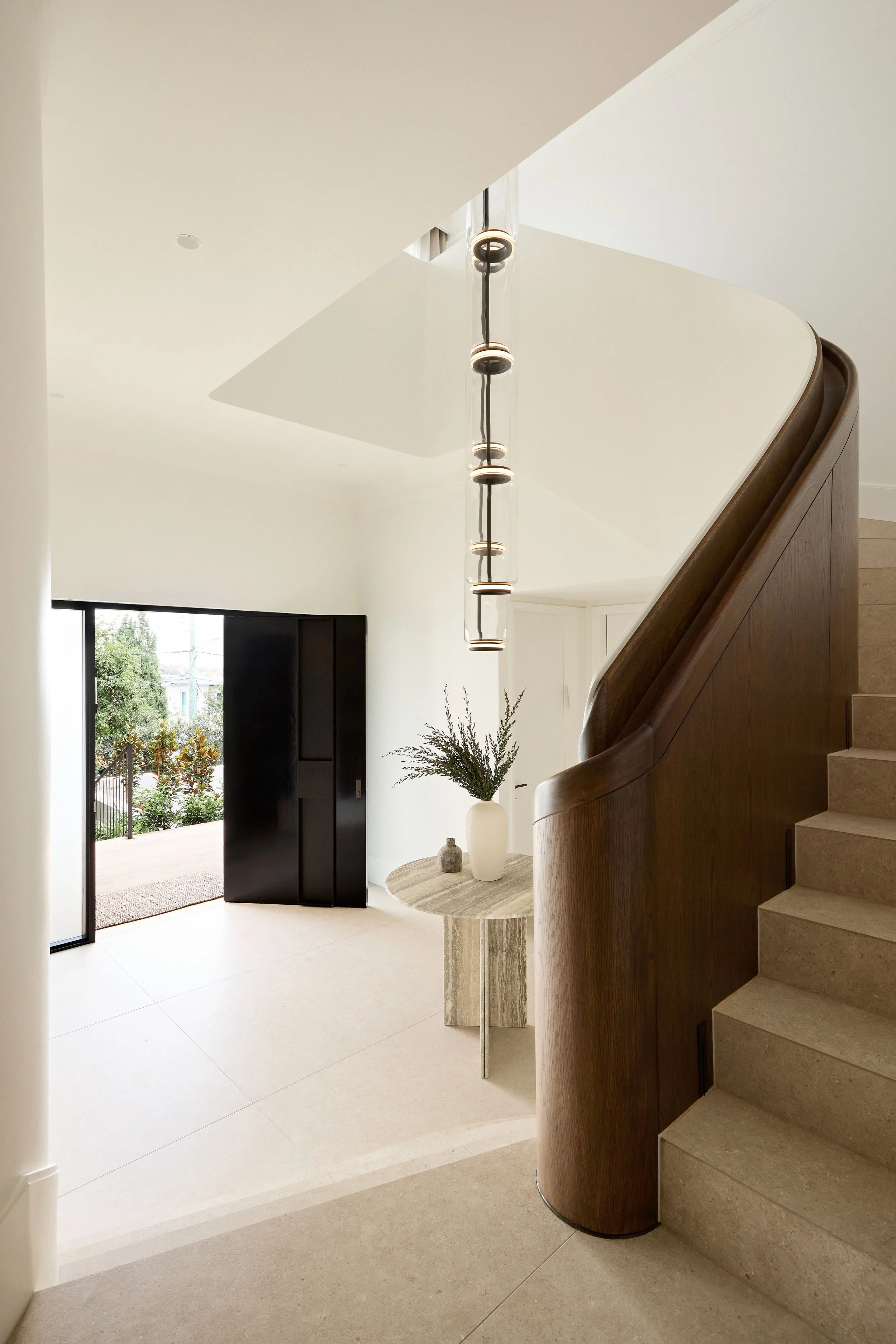 entry staircase with feature pendant light and table and front door open to garden