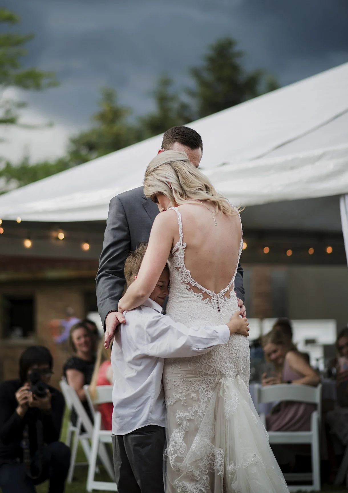 Bride and groom sharing their first dance with their son during a micro wedding ceremony in their toronto yard