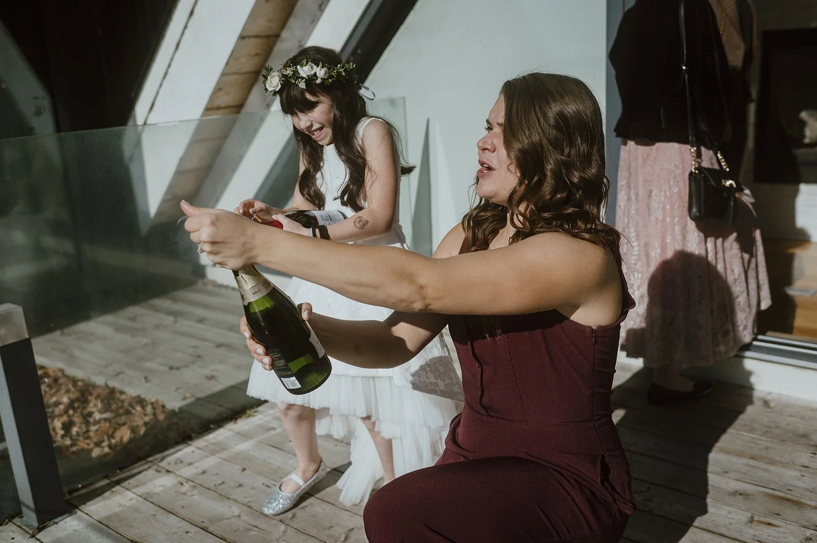 A woman on a baloney in the Drake Hotel in price edward county after an elopement ceremony. She is popping champagne bottle next to the flower girl