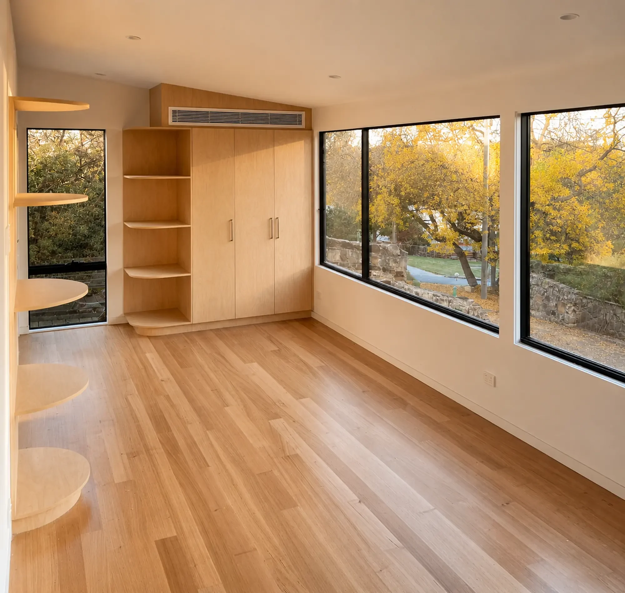 Light-filled modular home living room with timber flooring and built-in cabinetry in Victoria