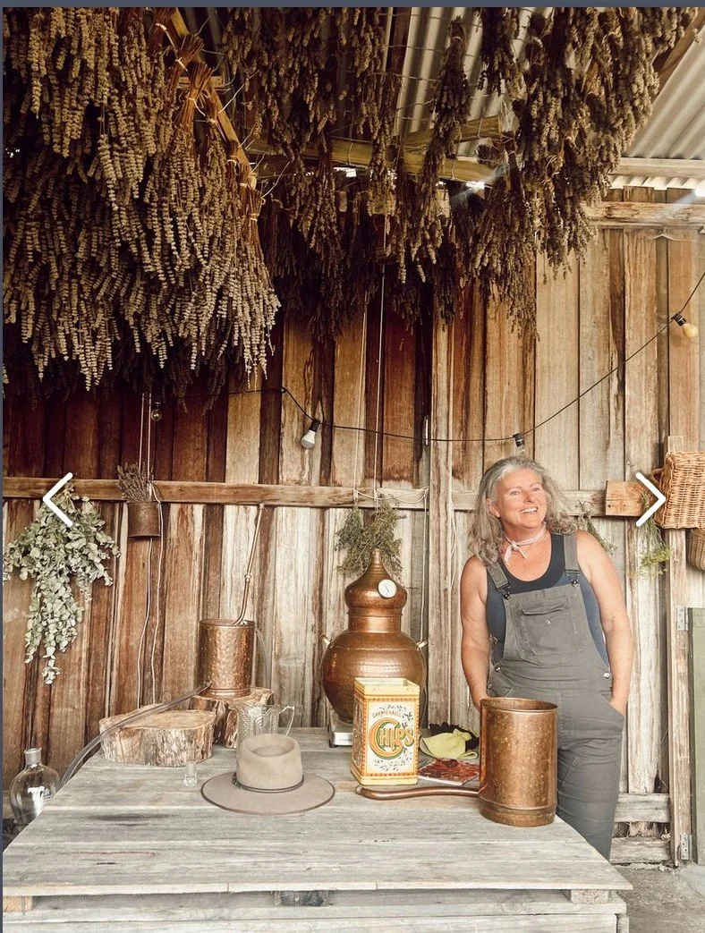 Woman standing in shed with distallation pot