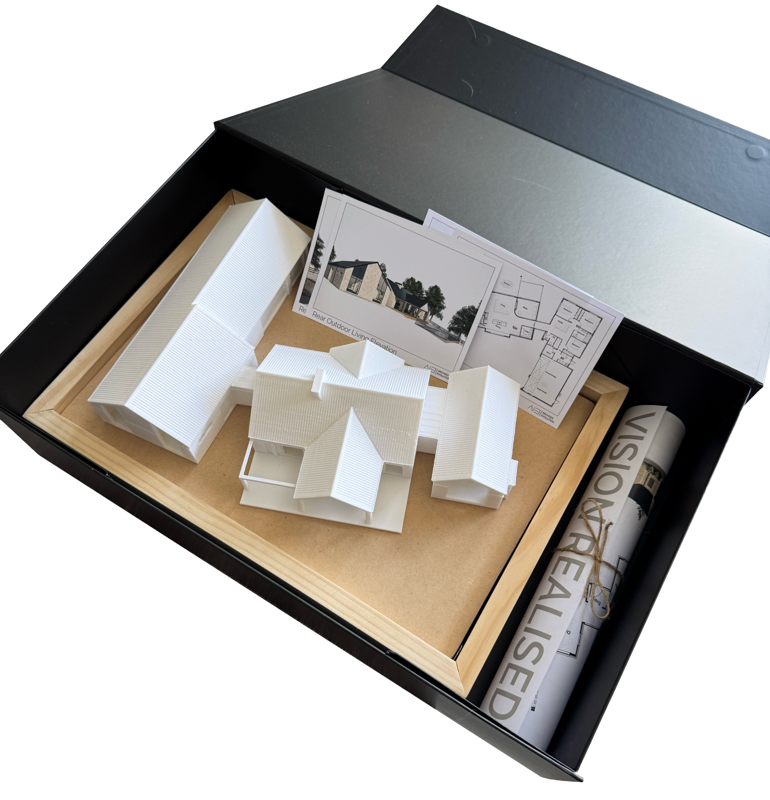 Architectural model of a house with detailed roof design, floor plans, a computer rendering, and rolled-up architectural plans in a presentation box.