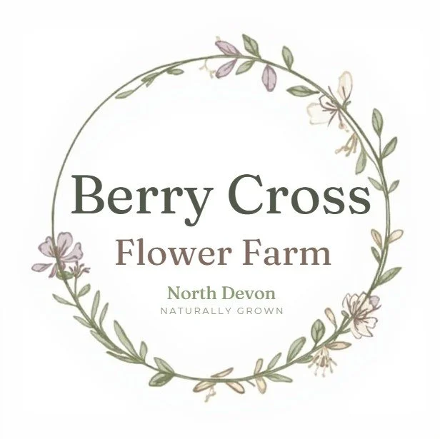 Logo for Berry Cross Flower Farm featuring a circular floral wreath with light purple and white flowers and green leaves, text reading 'Berry Cross Flower Farm, North Devon, Naturally Grown'.