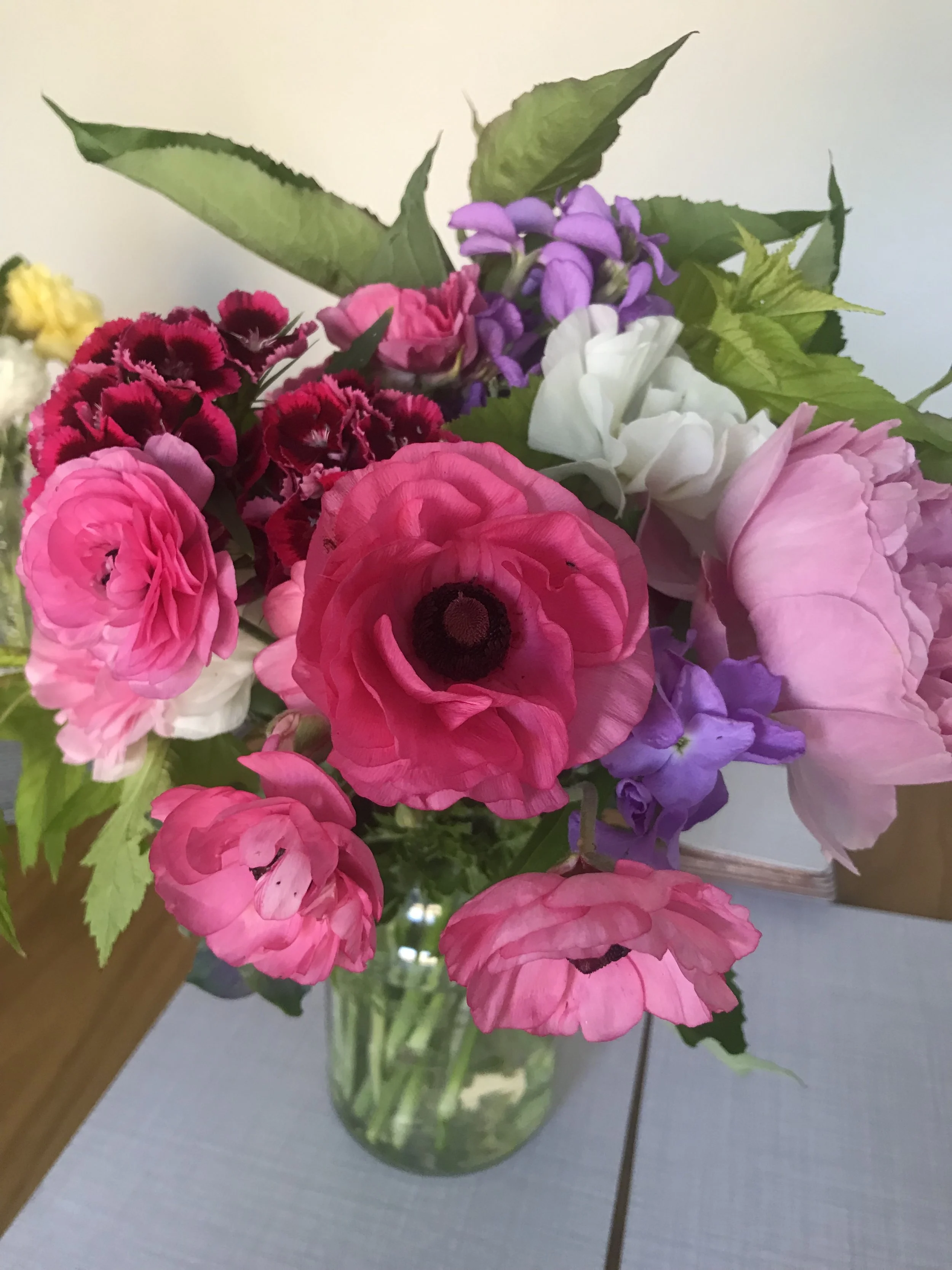A bouquet of various colorful flowers in a glass vase on a table.