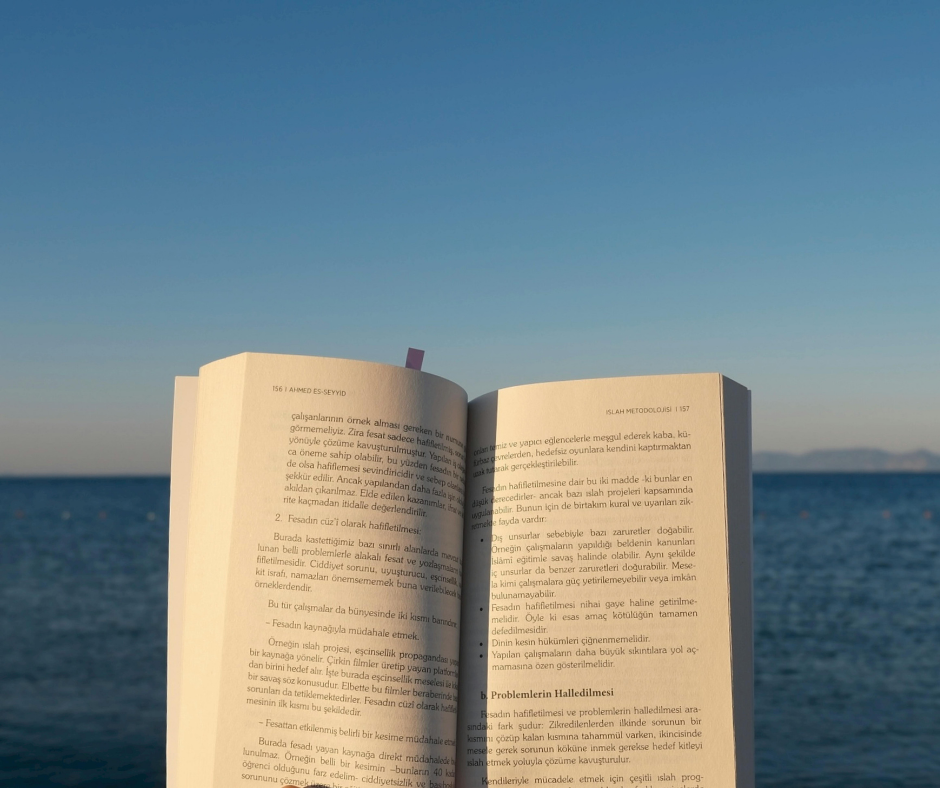 First-person perspective of an open book against a calm ocean horizon, symbolizing the return to valued living through ACT-I.