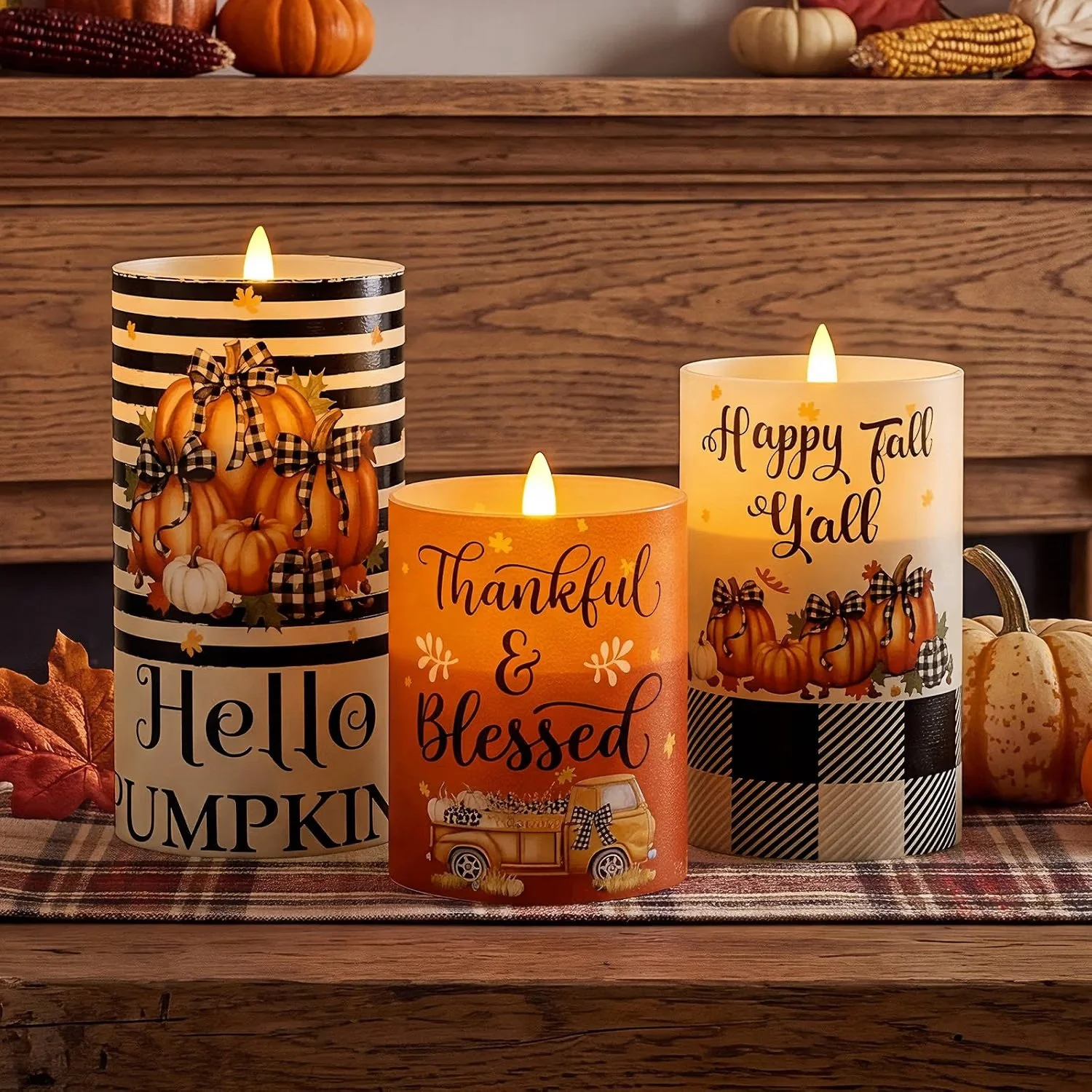 Three lit candles with fall and Thanksgiving decorations in the background.