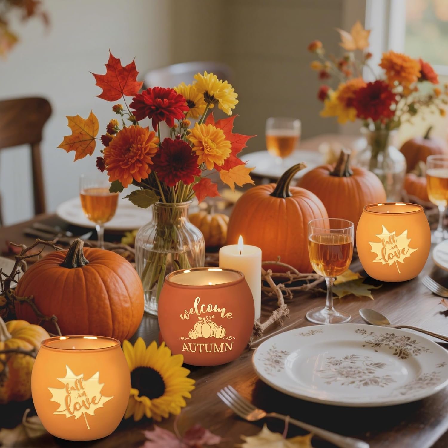 A fall-themed dinner table decorated with pumpkins, autumn leaves, sunflowers, candles, and floral arrangements, with