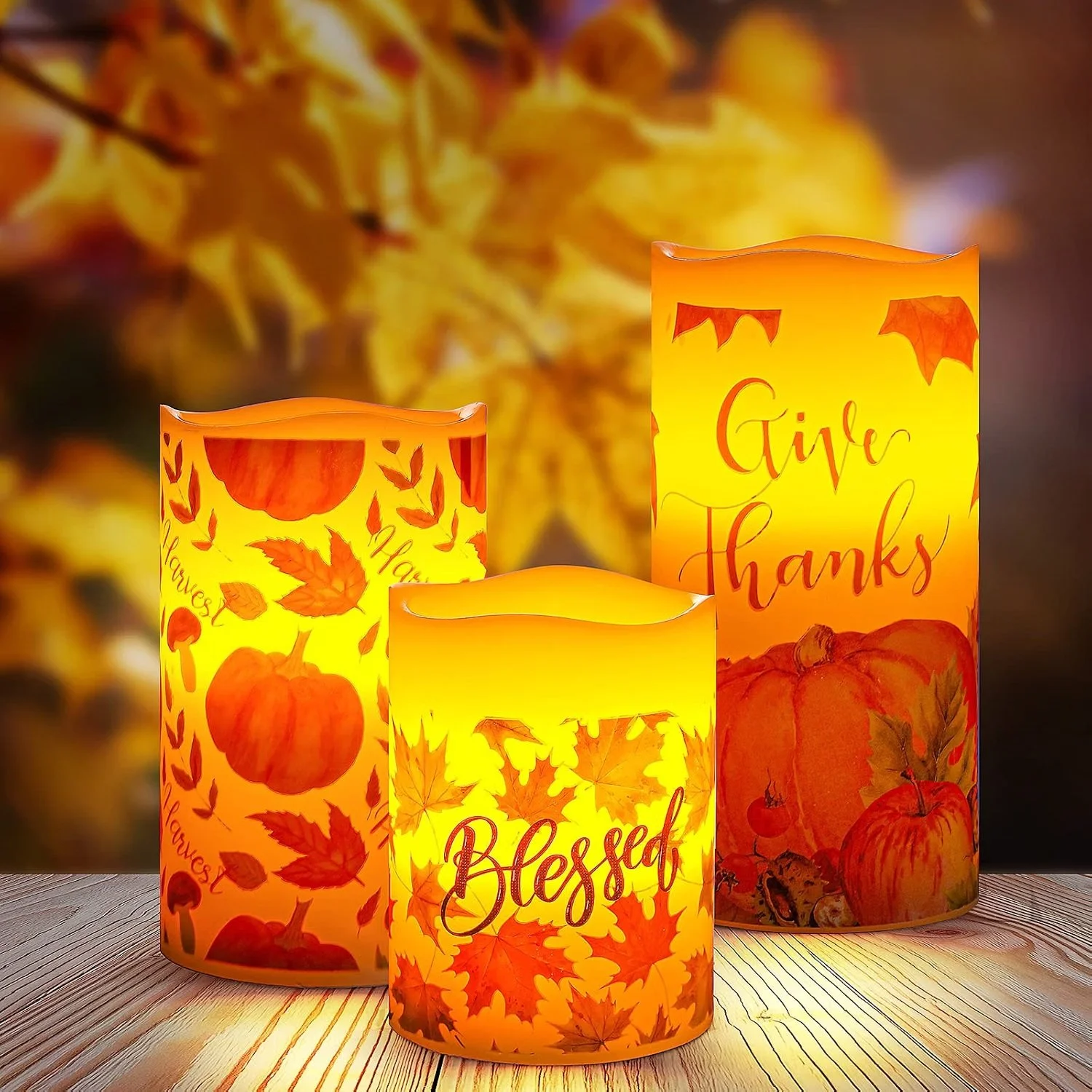 Three illuminated autumn-themed paper lanterns with leaf and pumpkin designs, displaying words like "Blessed" and "Give Thanks."