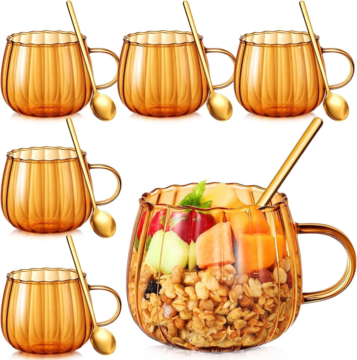 Orange glass mugs with gold spoons, one mug contains fruit salad with melon, apple, and granola.