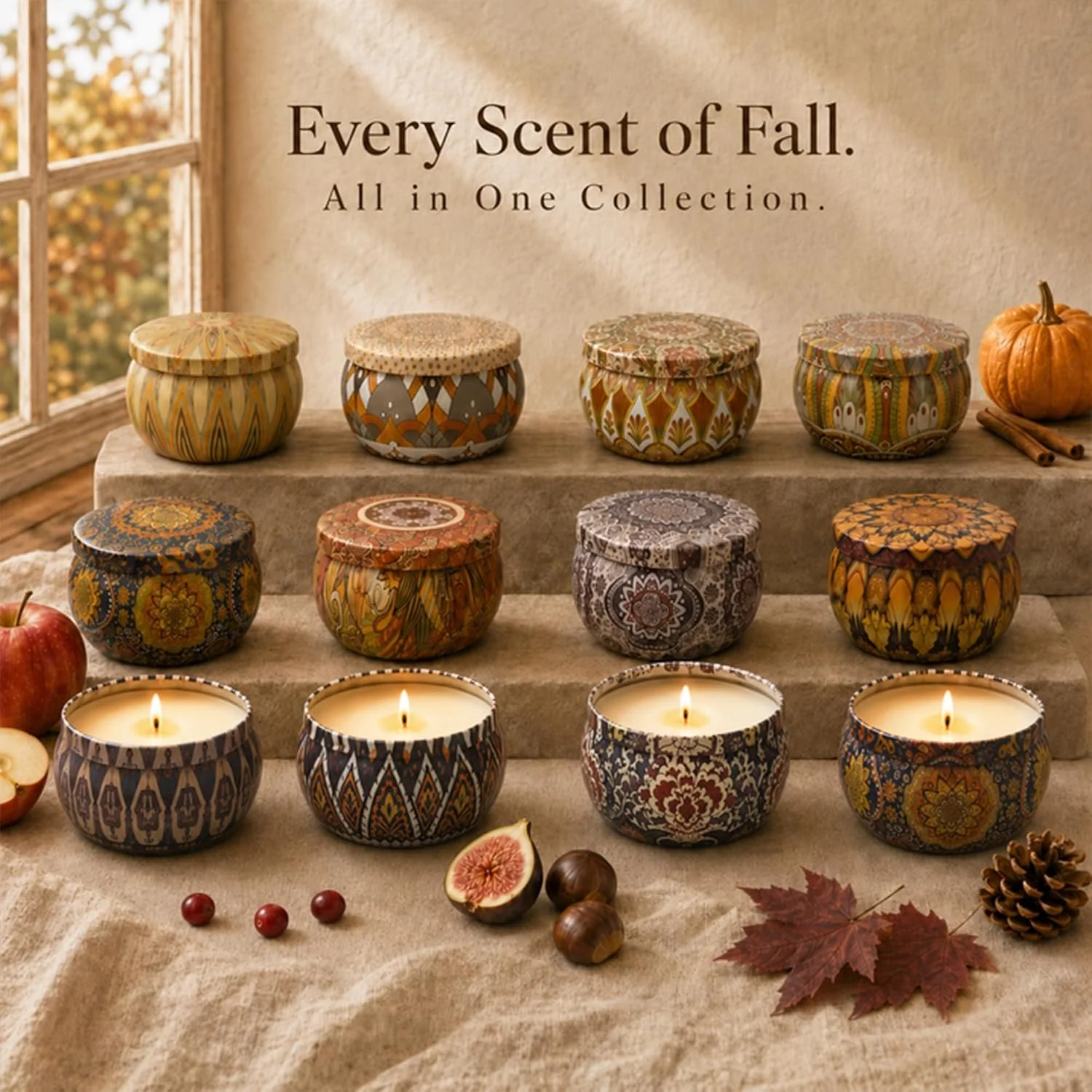 A display of decorative fall-themed candles in colorful patterned containers, arranged on beige fabric with autumn leaves, apples, figs, cranberries, walnuts, pinecones, and cinnamon sticks around them. The background features a window with an autumn view and the phrase 'Every Scent of Fall. All in One Collection.'