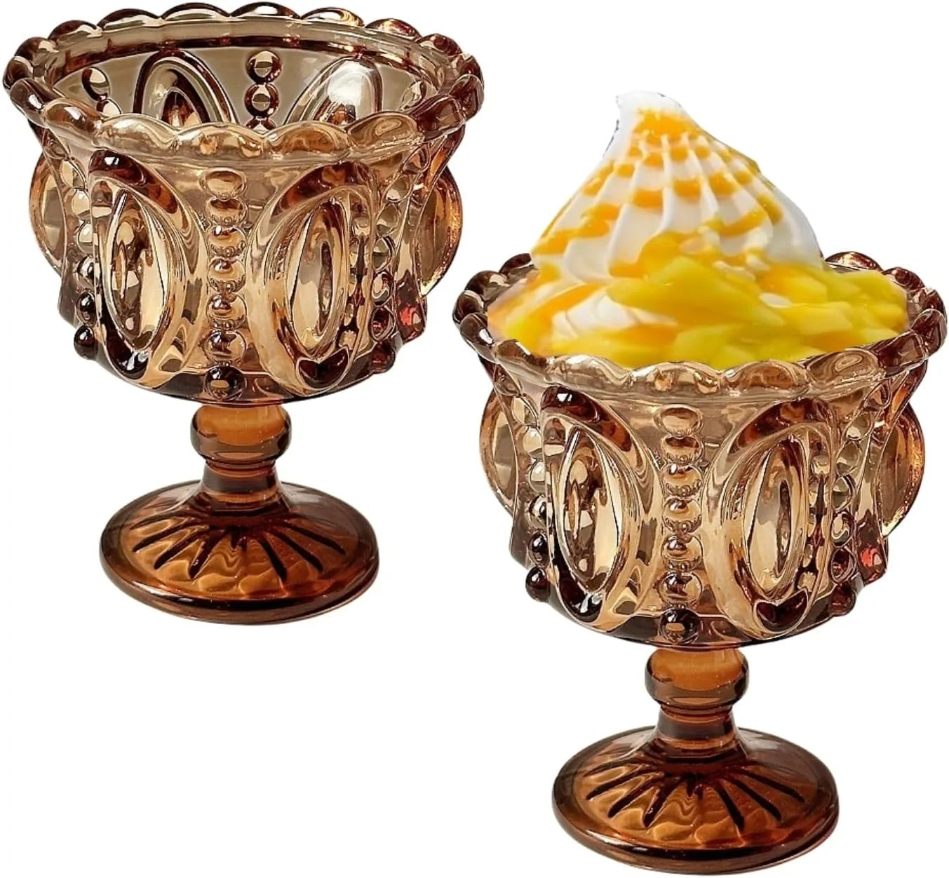 Two ornate amber glass goblets, one filled with soft serve ice cream topped with yellow syrup.