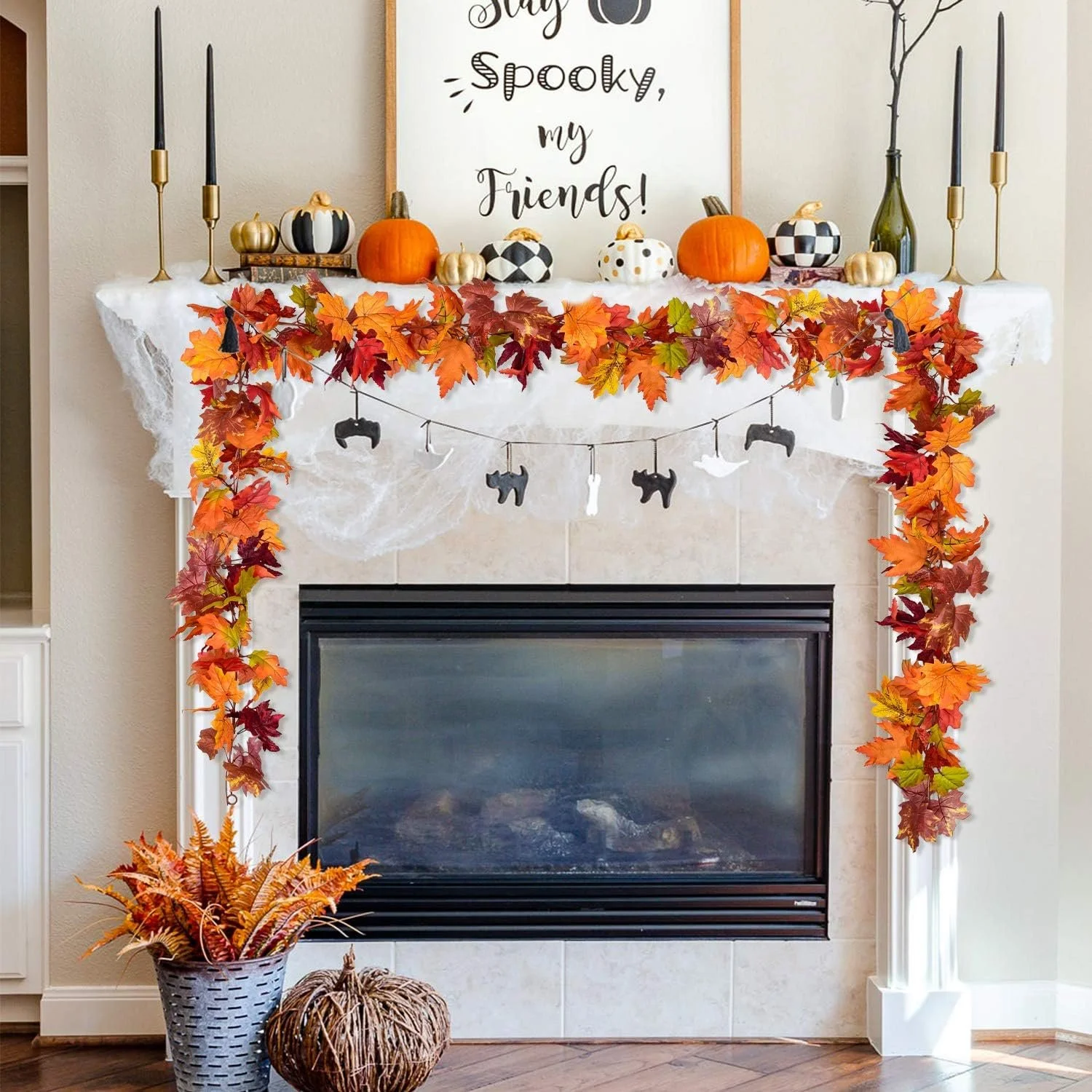 Living room fireplace decorated for fall with autumn leaves, pumpkins, and Halloween-themed garland, with a framed sign saying 'Say Spooky, my Friends!', flanked by black candles and decorative bottles.