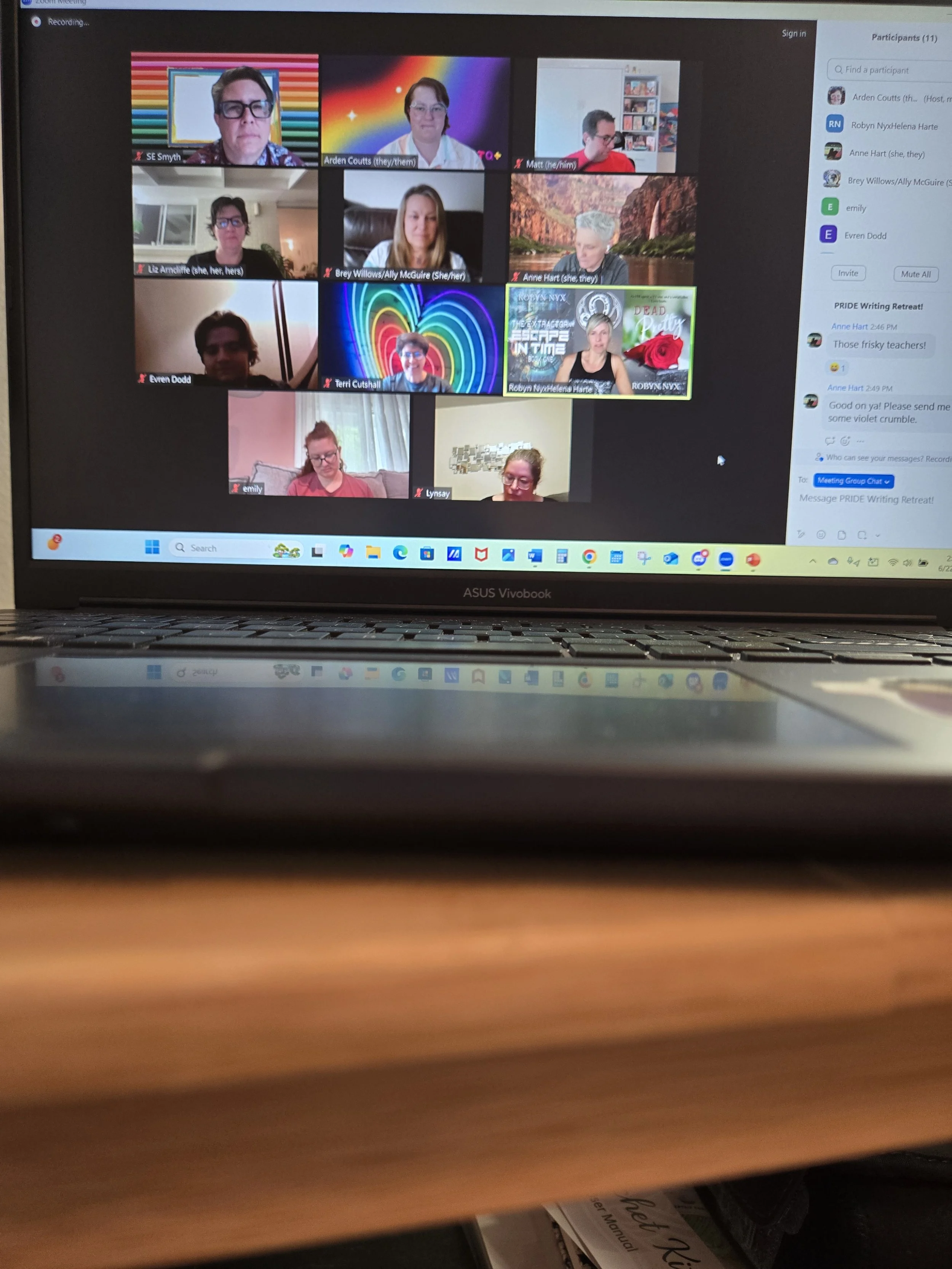 Laptop screen displaying a Zoom video conference with eleven participants, some with colorful virtual backgrounds, and a chat sidebar on the right.