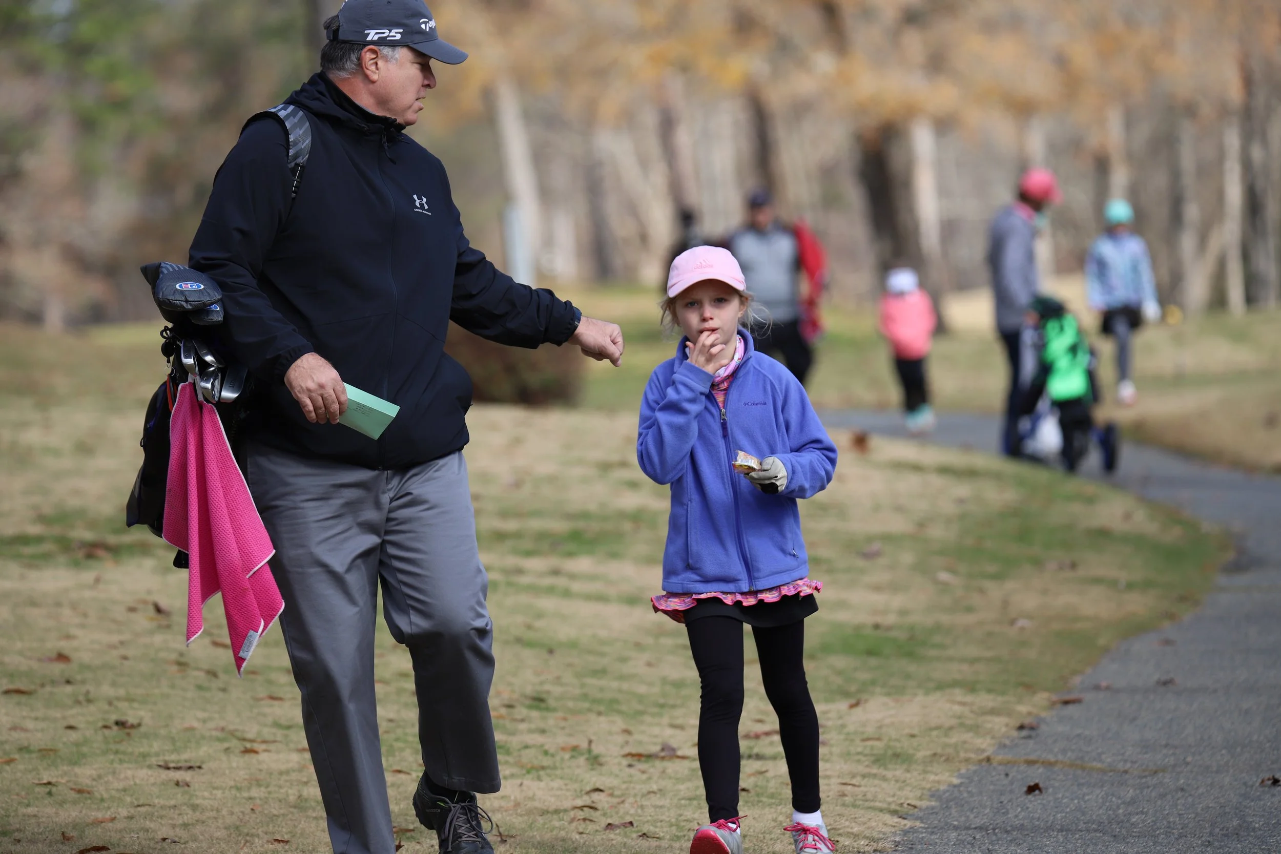 Young junior golfer walking with caddy