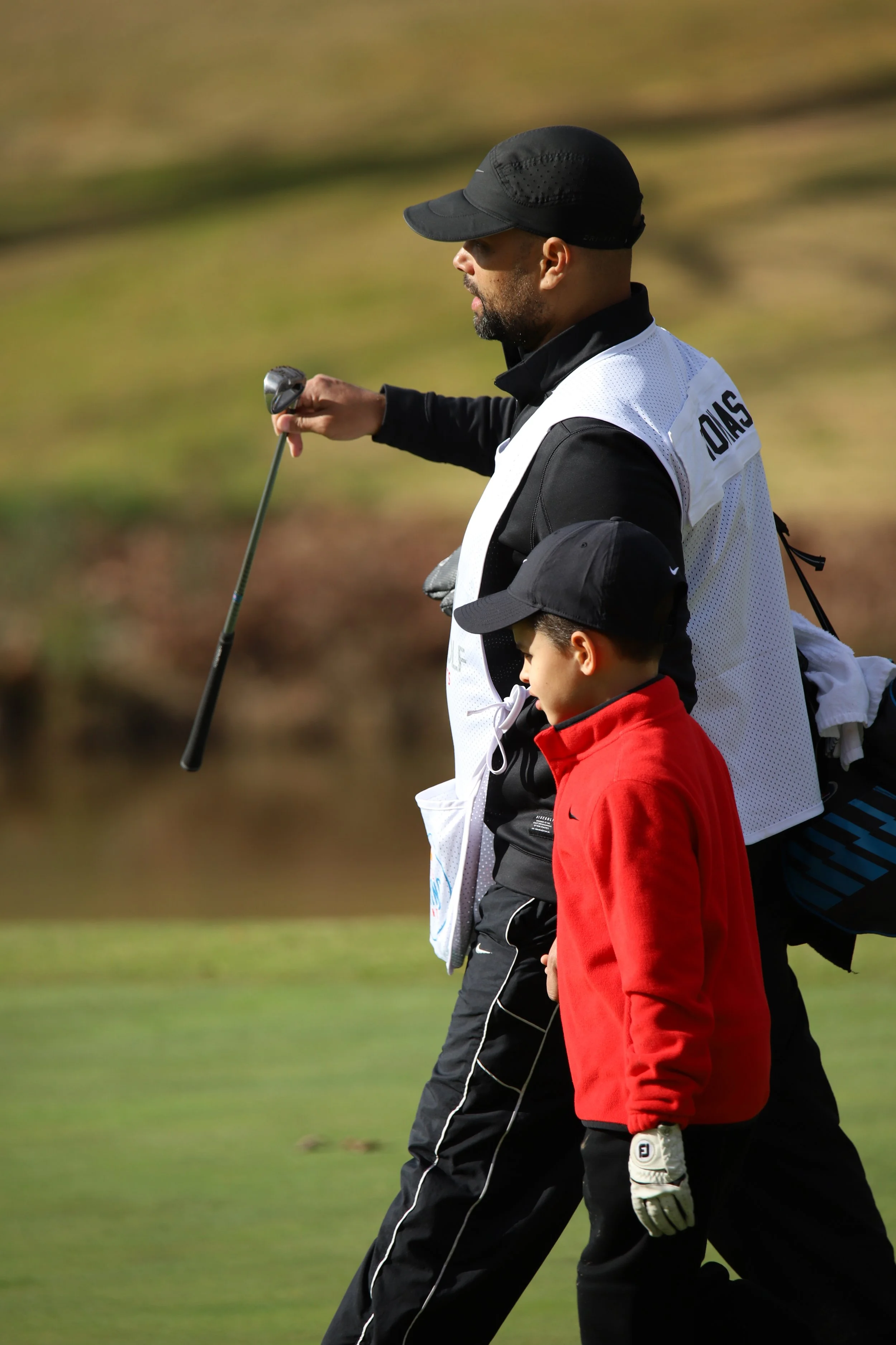 Junior golfer with caddy during golf event