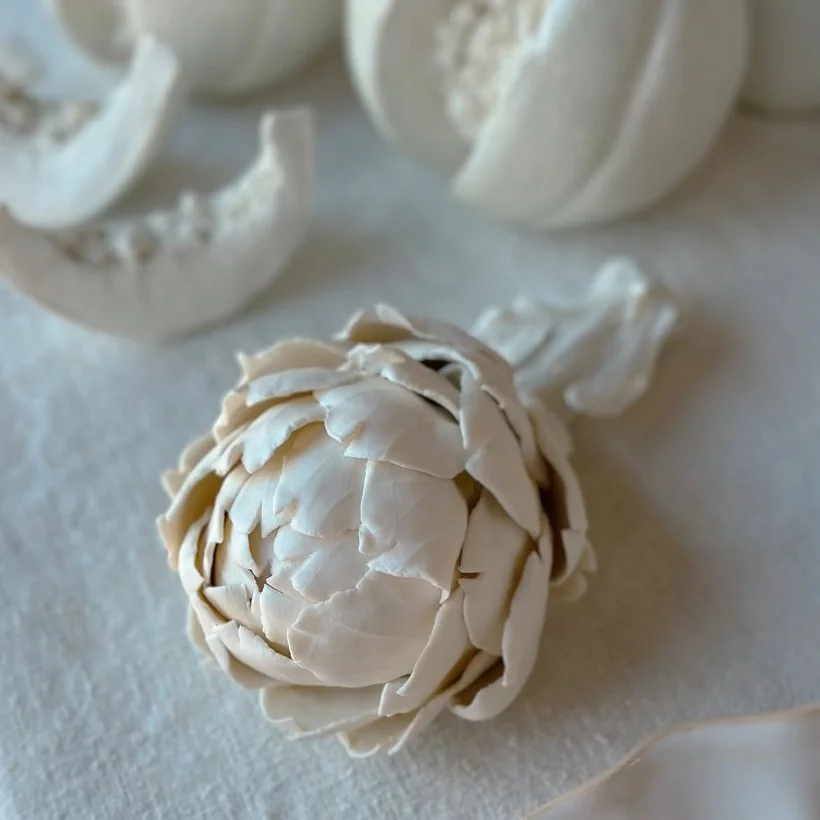 Une boule d'artichaut en coquillage blanc, entourée de morceaux d'os de seiche.