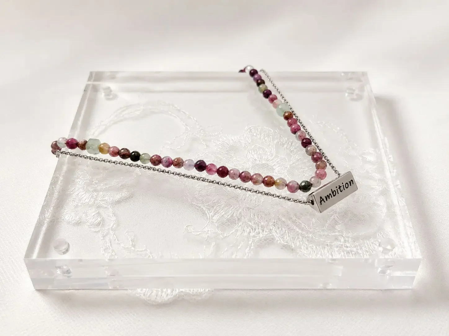 Scented emotions spring diffuser double strands necklace, with semi precious stones and meaningful words engraved on pendant. showcased on a spring color-theme display to remind you to embrace new beginnings, to grow.