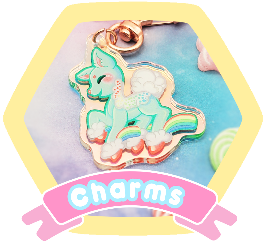 A colorful enamel keychain featuring a smiling, cartoon-style unicorn with a rainbow-colored tail and clouds, attached to a gold keyring, against pastel background with a pink banner reading 'charms'.