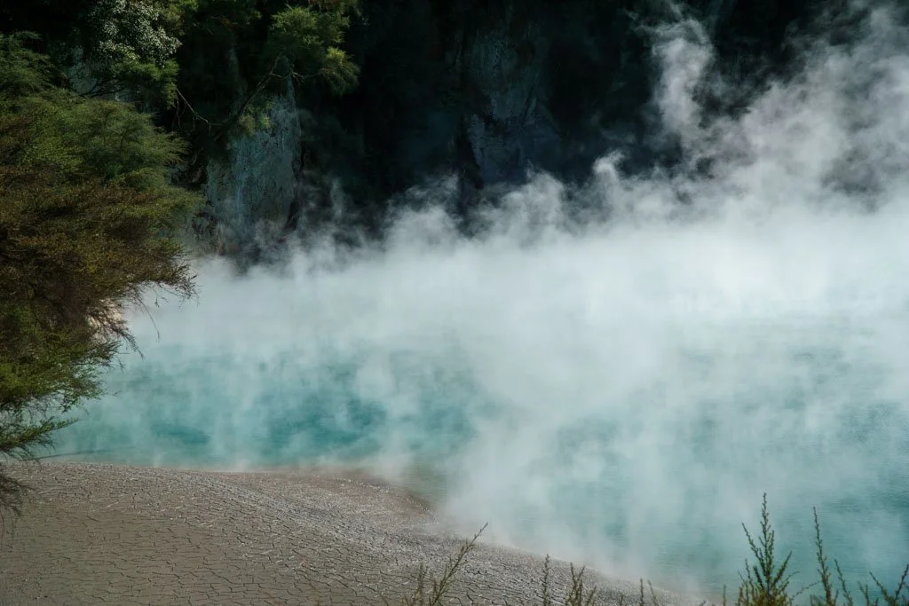 Steam rises from a bright blue pool at Waimangu