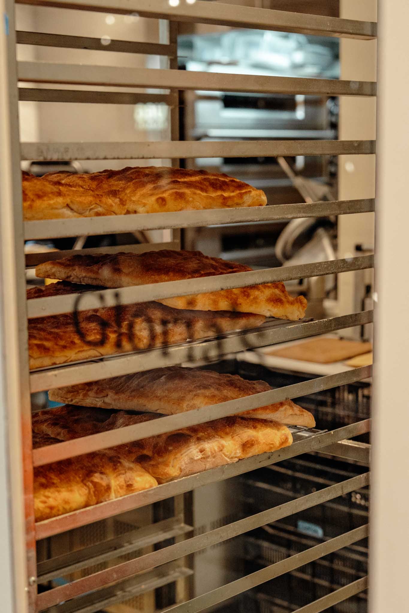 A window that reads Gloria's with bread on shelves on the other side