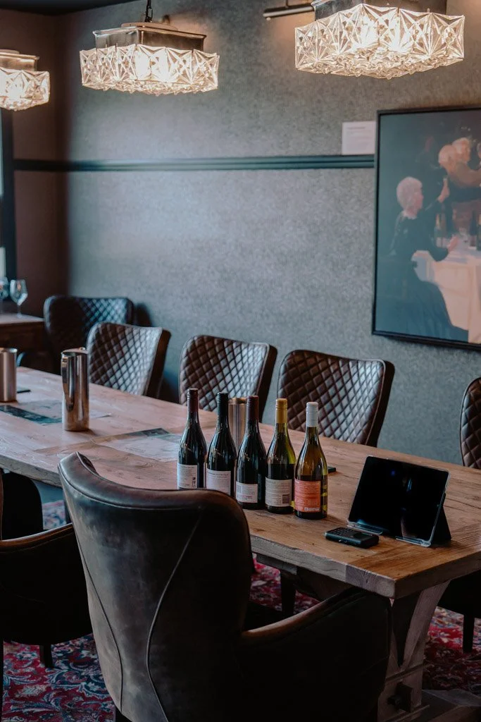 Bottles of wine are lined up on a wooden table