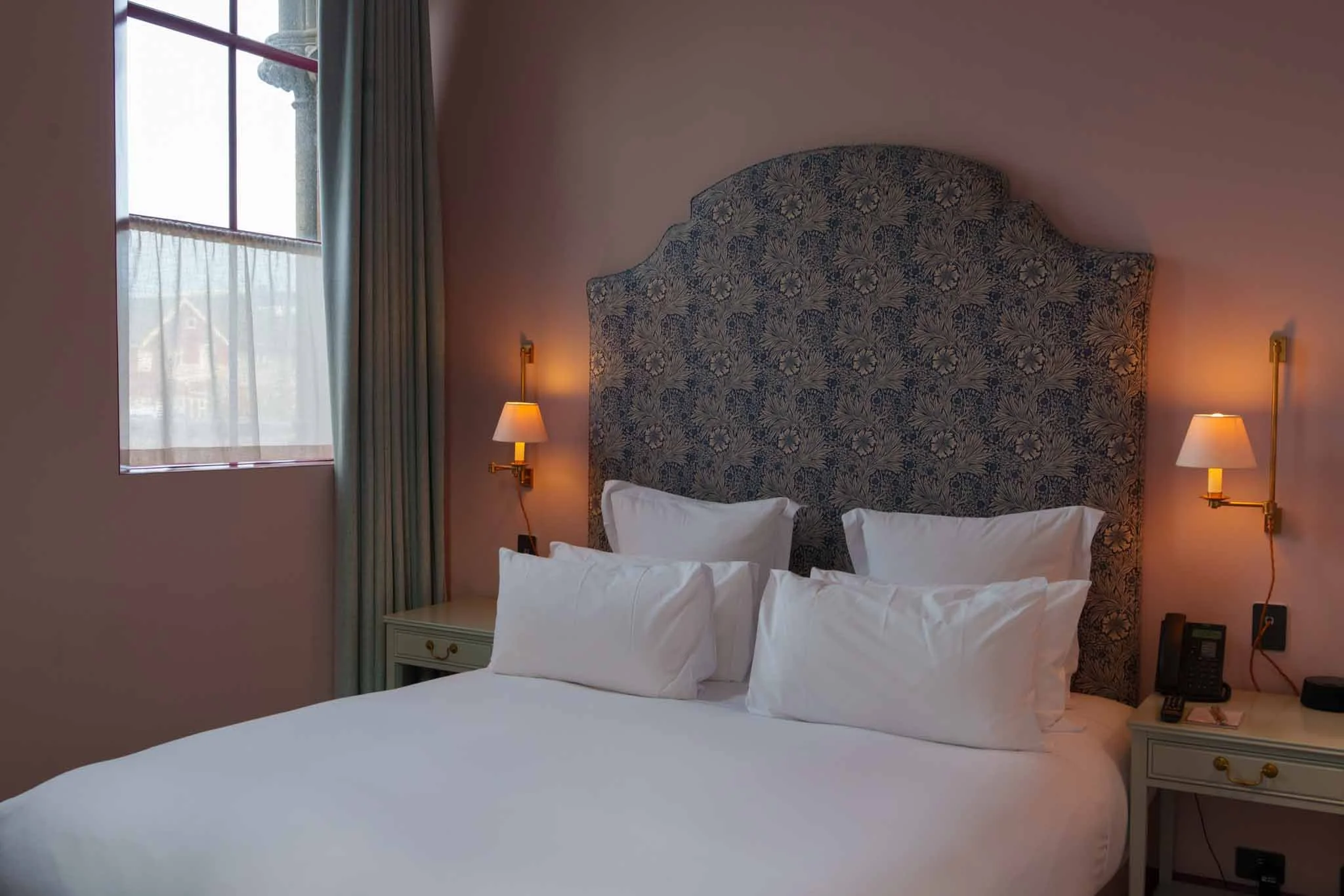 A hotel room with pink walls and blue curtains
