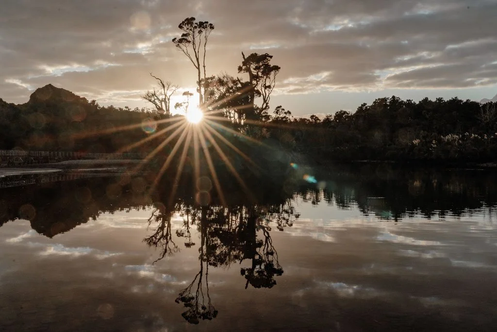 The sun rises over a calm lagoon on the west coast of the south island