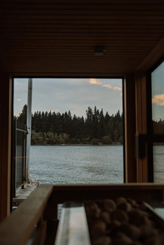 A lake and mountains are visible across the hot stones of a sauna