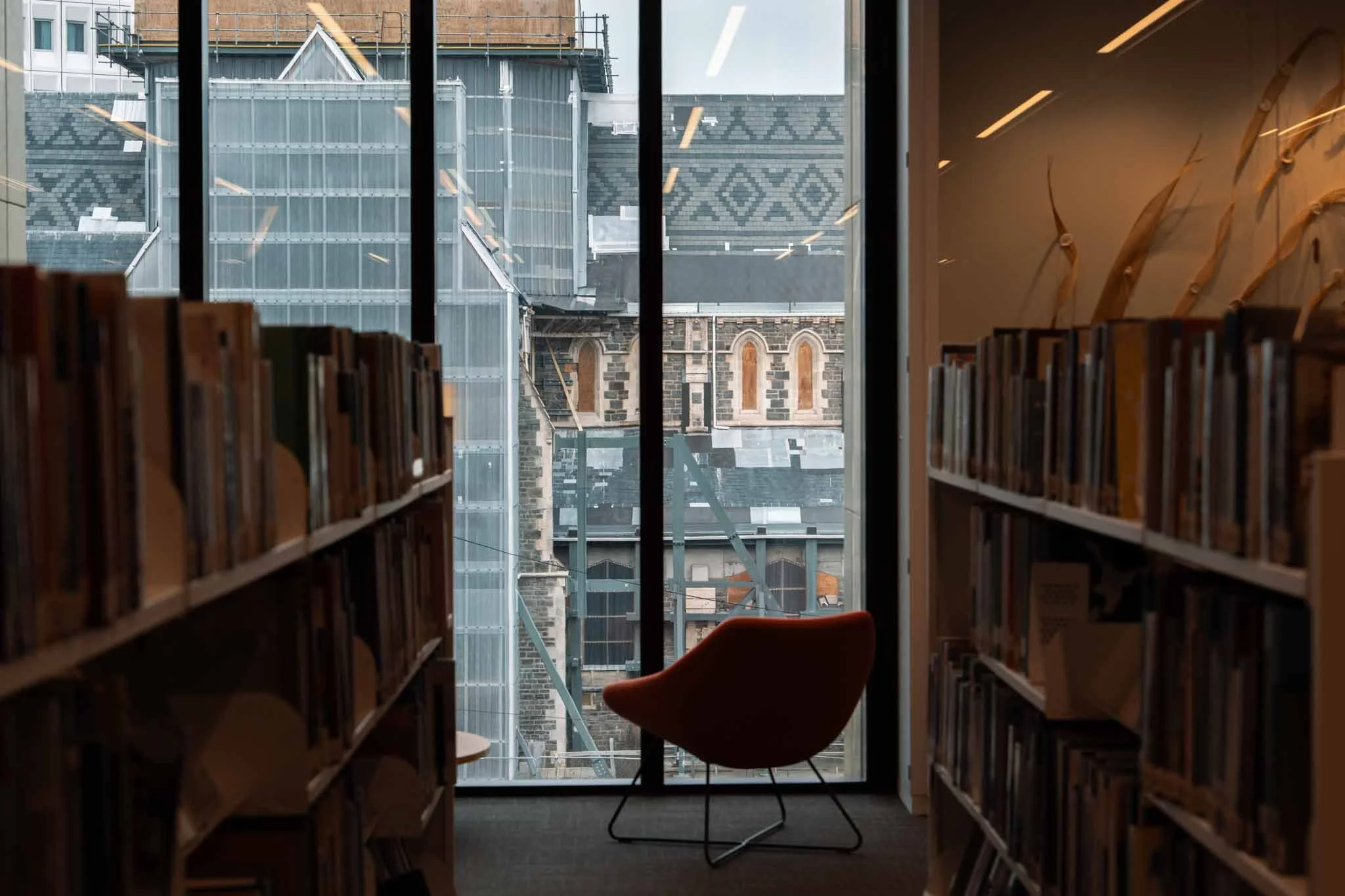 A chair is positioned in front of a window with a view of the Christchurch cathedral