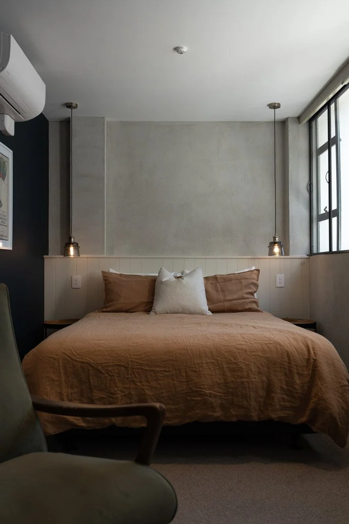 A bed with a rust coloured duvet cover in the Cobbler Hotel in Wellington