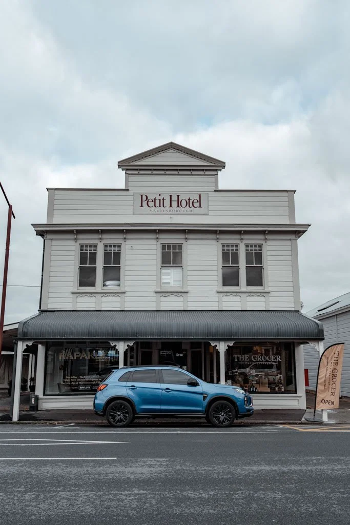 A blue car is parked outside the facade of an old fashioned building