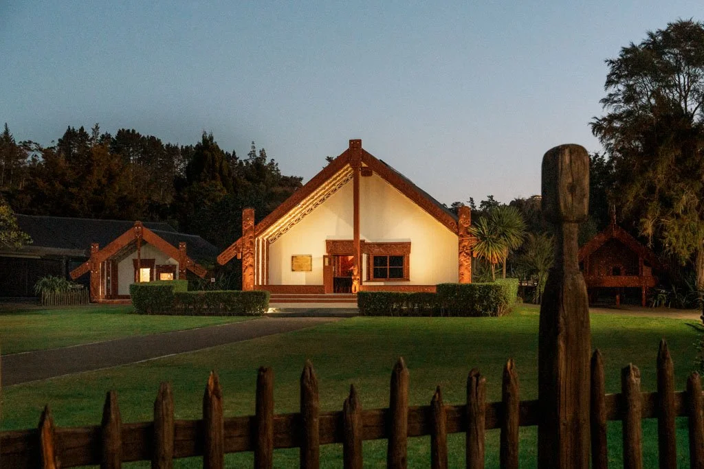 A traditional Maori meeting house is lit up by warm lights
