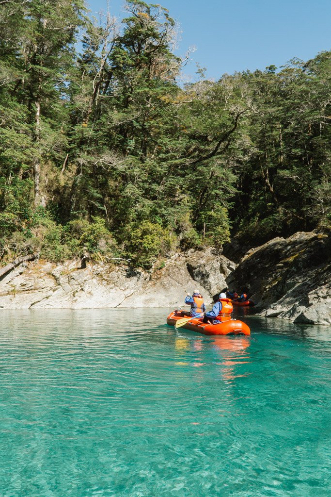 Two people paddle an inflatable canoe across bright blue water