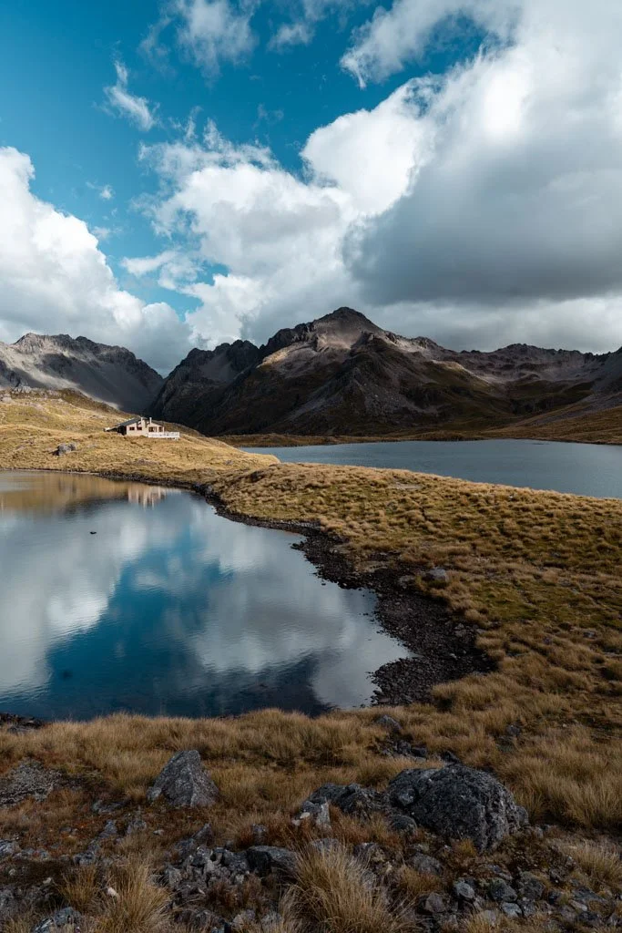 A small mountain hut is reflected in a calm lake