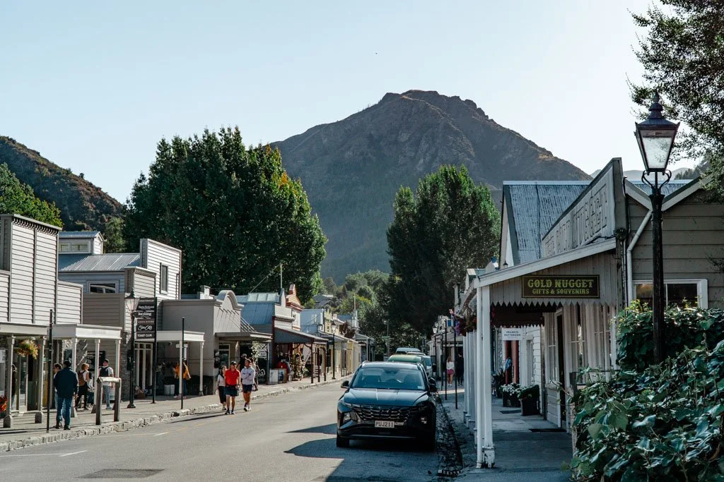 Tourists stroll down a quaint street with old timey shopfronts