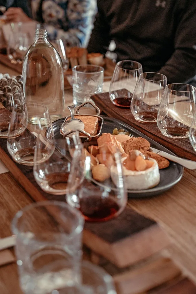 Glasses of wine and platters of cheese, crackers and dried fruit on a wooden table at Carrick winery