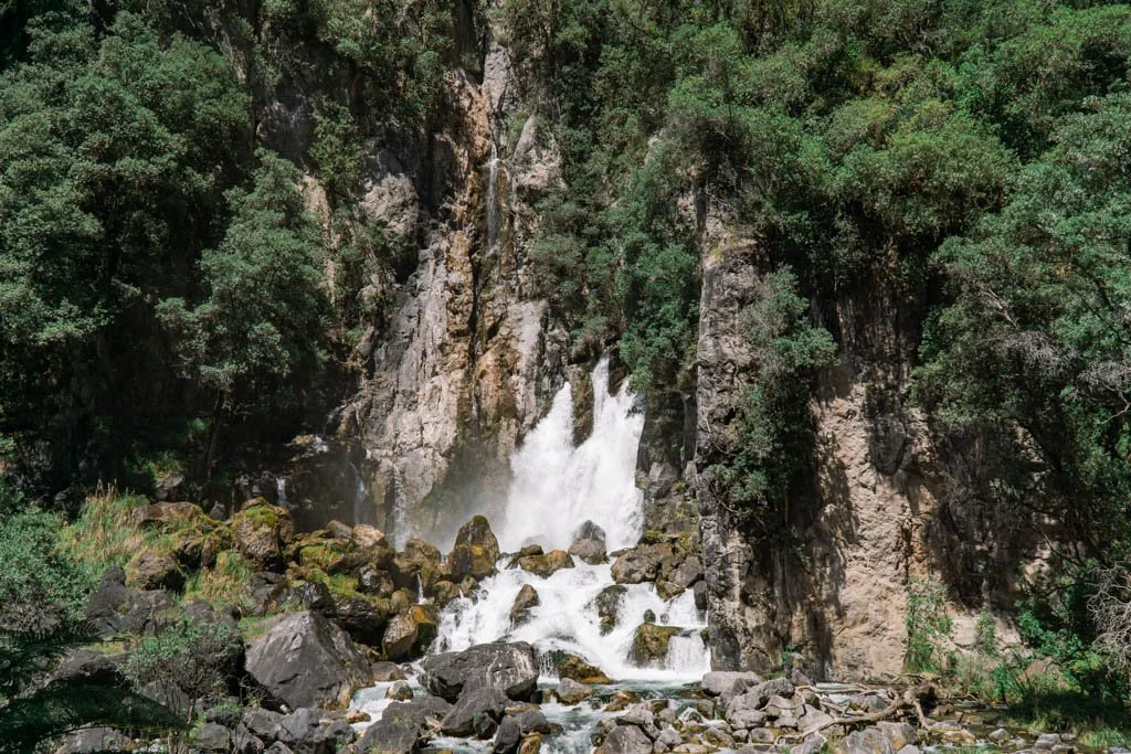 A waterfall pours straight out of a cliff face