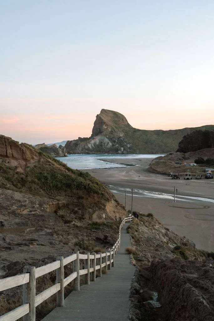 A walking trail leads down to a beach with a rocky outcrop visible in the distance