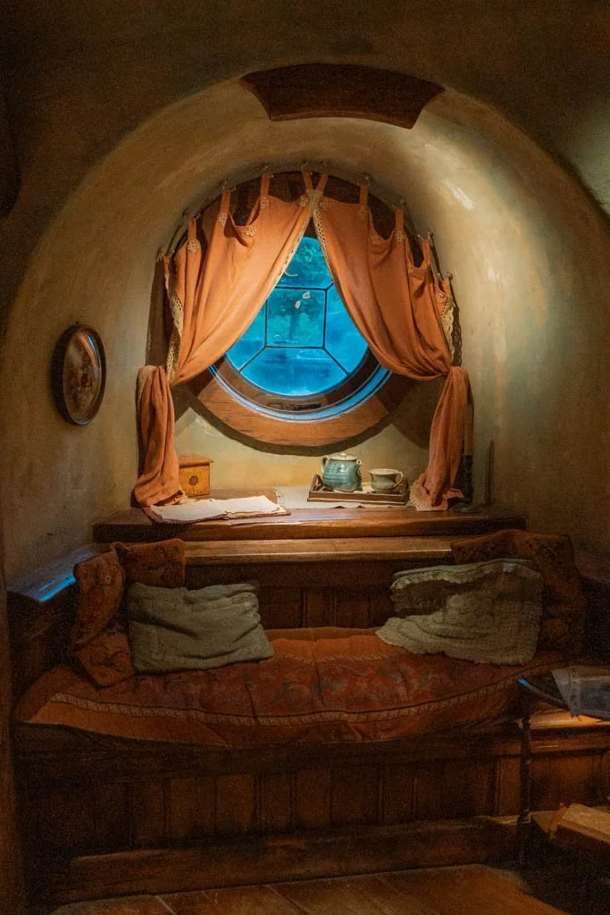 Inside a Hobbit hole, a couch in front of a small round window