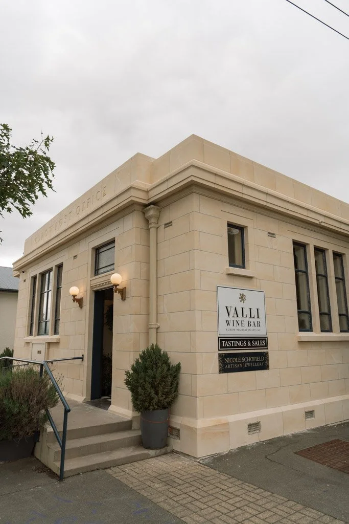 A sign on the outside of a white brick building reads Valli wine bar